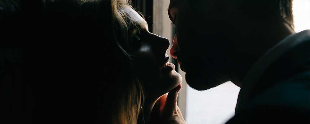 Couple sharing a passionate kiss and teasing each other during a night at Club 390, enjoying the intimate and exciting atmosphere.